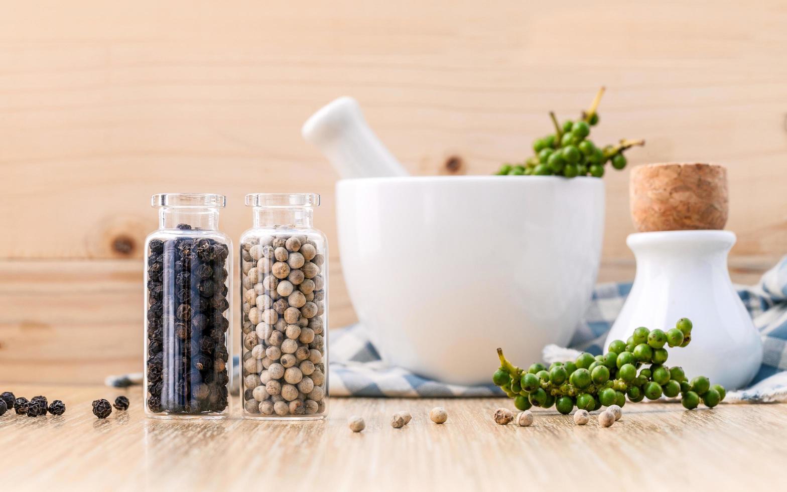 Assorted spice bottles with mortar on wooden background photo