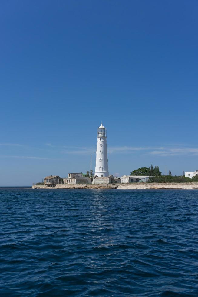 Seascape of a white lighthouse at Cape Tarkhankut with a clear blue sky in Crimea photo