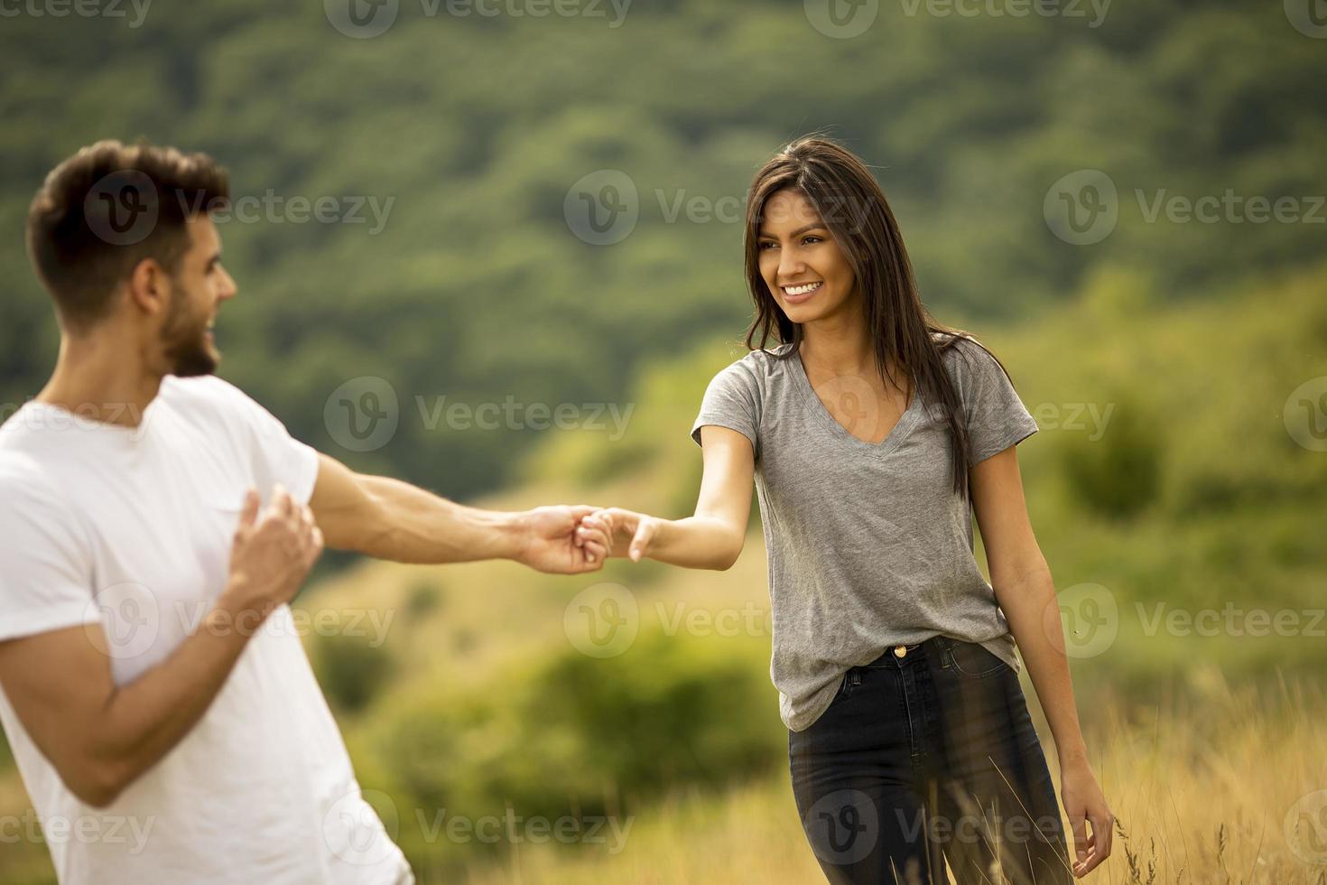Happy young couple in love walking through grass field photo