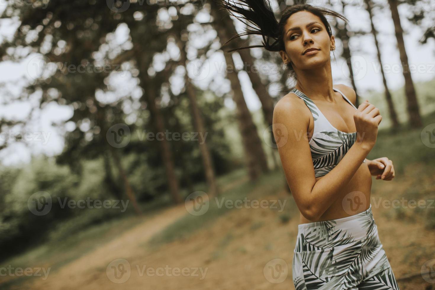 Young fitness woman running at forest trail photo