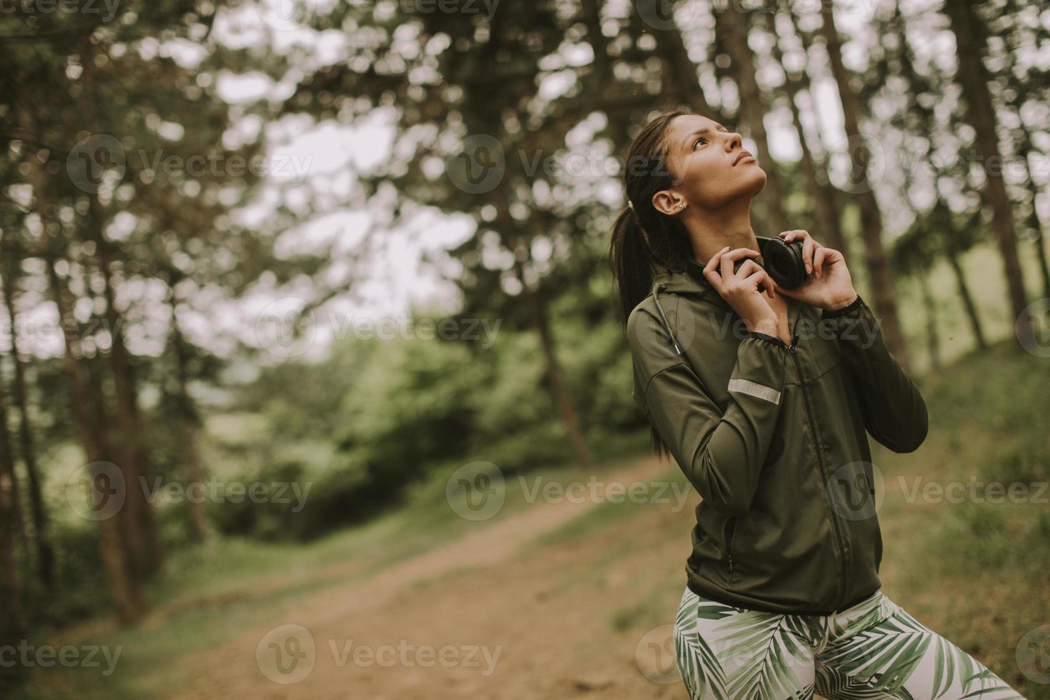 Hermosa joven corredora escuchando música y tomando un descanso después de trotar en un bosque foto