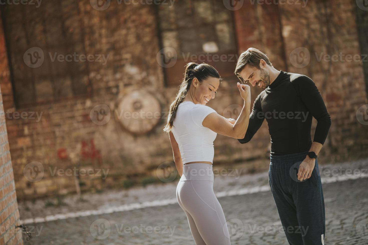 Mujer joven haciendo ejercicio de estiramiento después de trotar con su entrenador personal foto