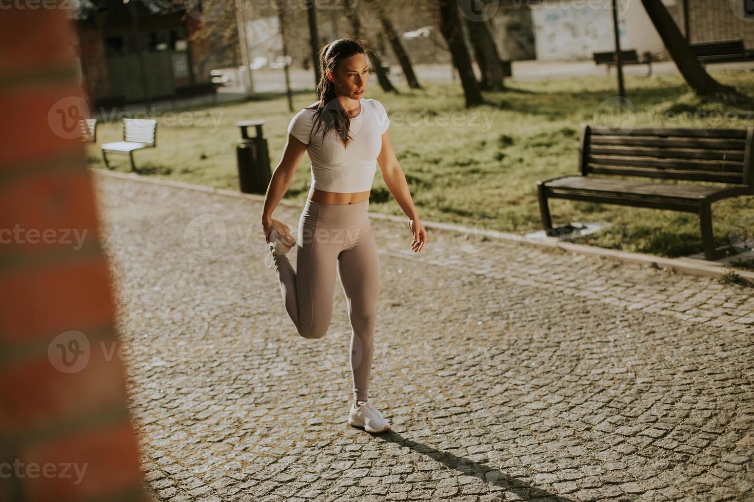 Mujer joven que se extiende durante el entrenamiento en el entorno urbano. foto