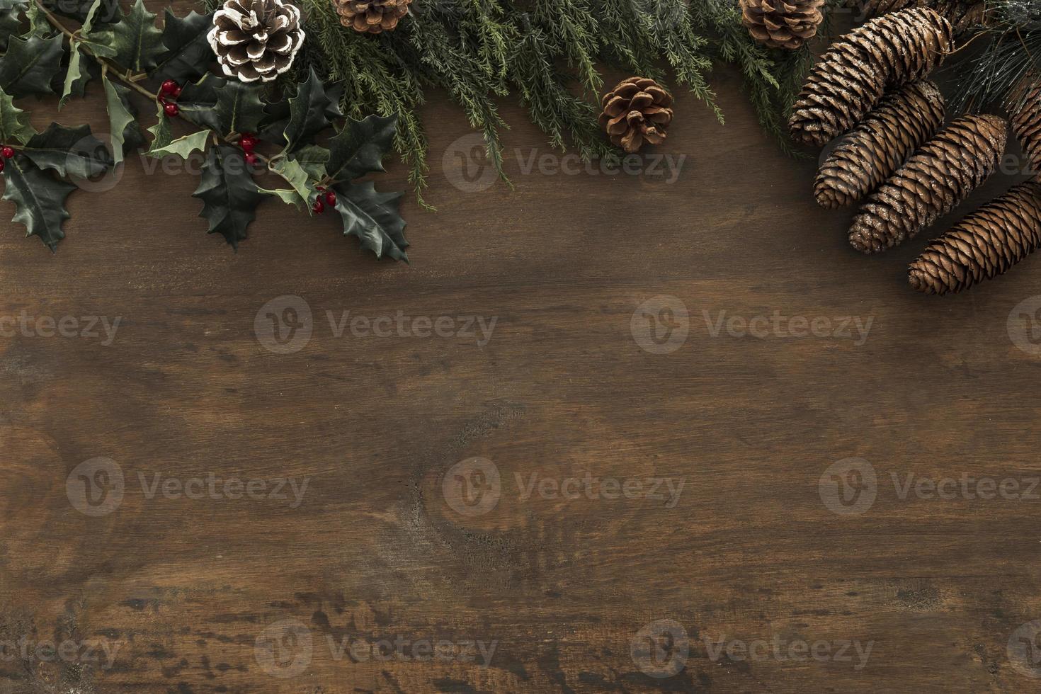 Holly branches with cones on wooden table photo