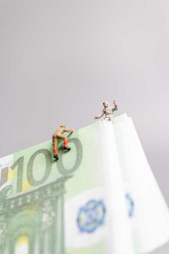 Miniature people, climber climbs on a Euro banknote, business concept. photo