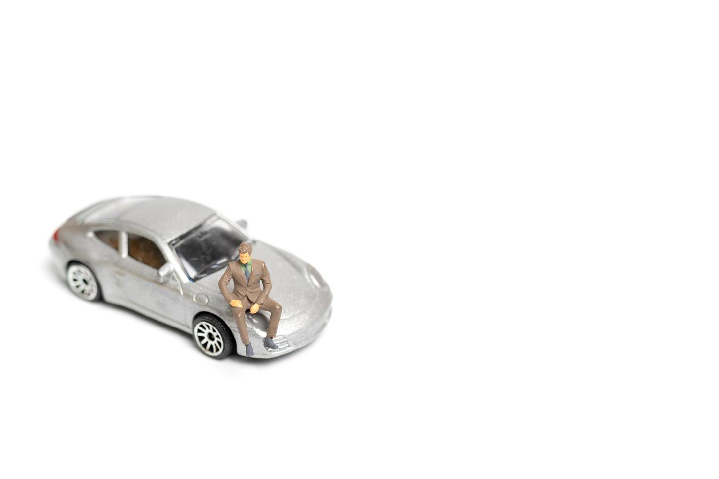 Miniature people, businessman sitting on a car and copy space for text photo