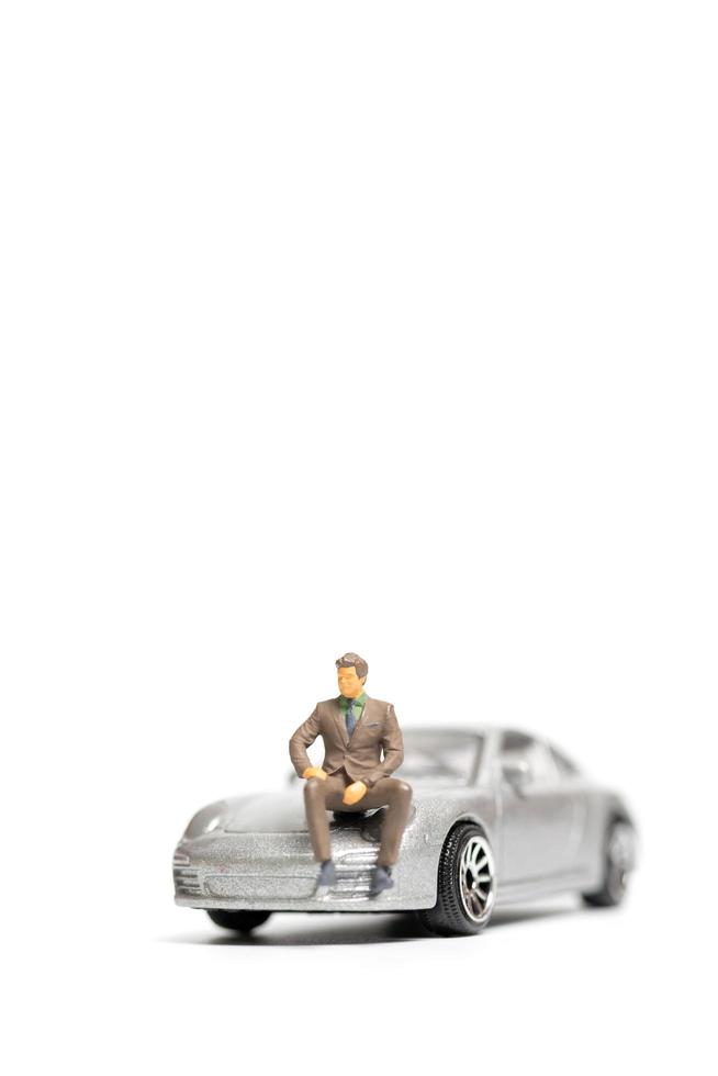 Miniature people, businessman sitting on a car and copy space for text photo