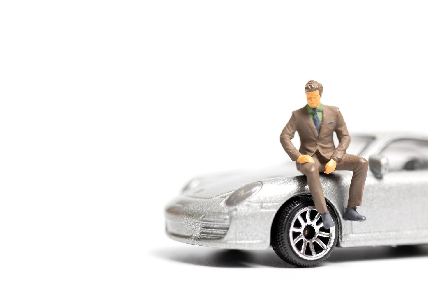 Miniature people, businessman sitting on a car and copy space for text photo