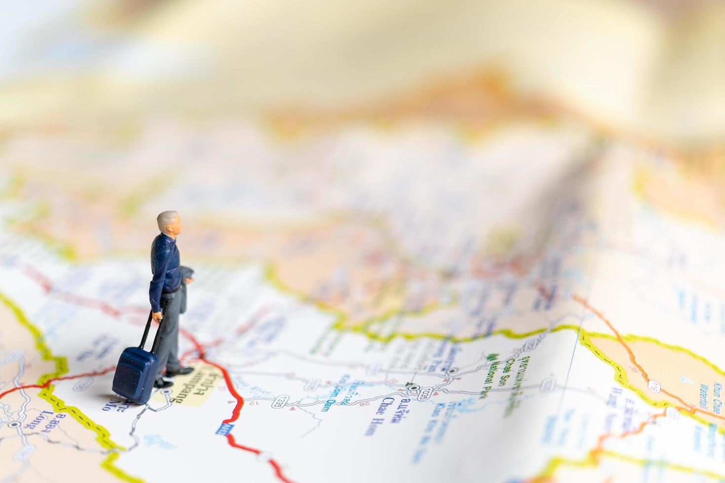 Miniature businessman standing on map, travel concept photo