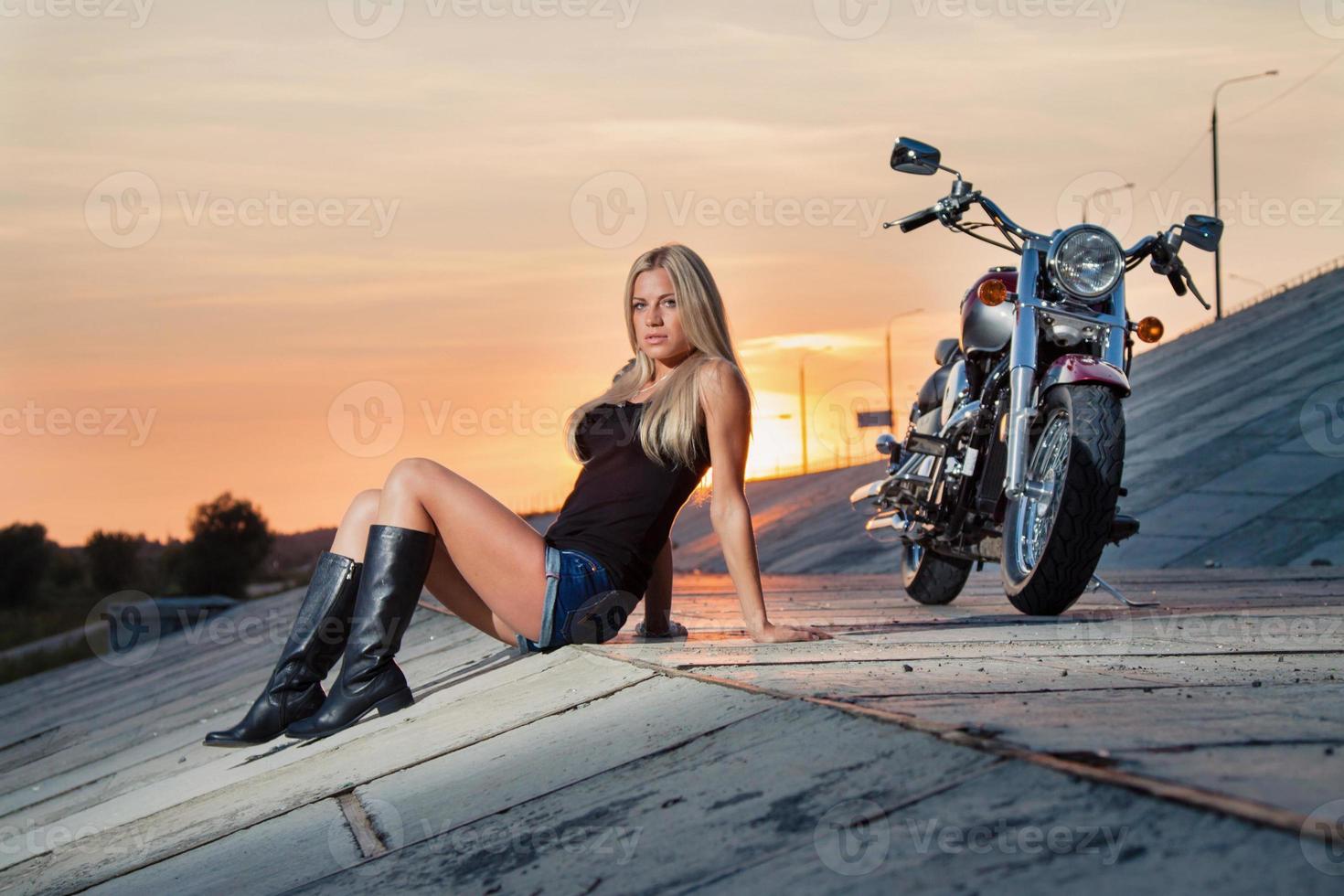 sexy rubia sentada cerca de su motocicleta foto