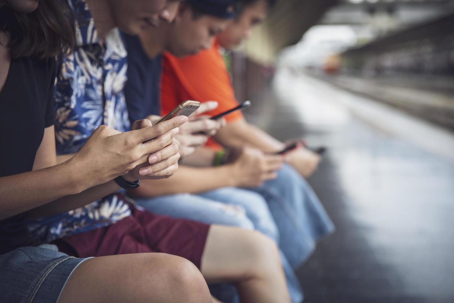 Group of friends using digital smartphones outdoors having fun with technology trends, teen lifestyle social media concept photo