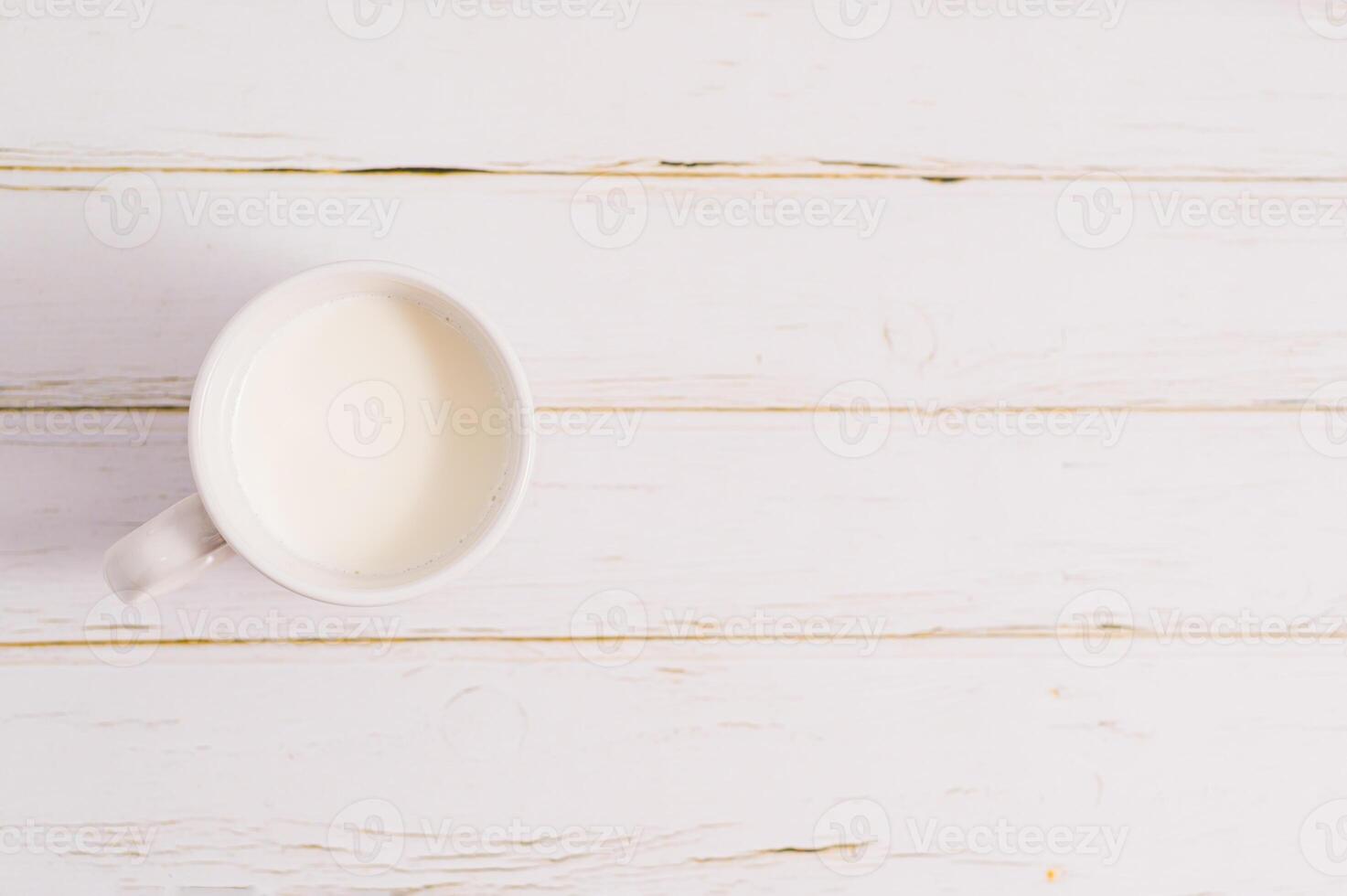 A cup of milk on a white wooden table photo