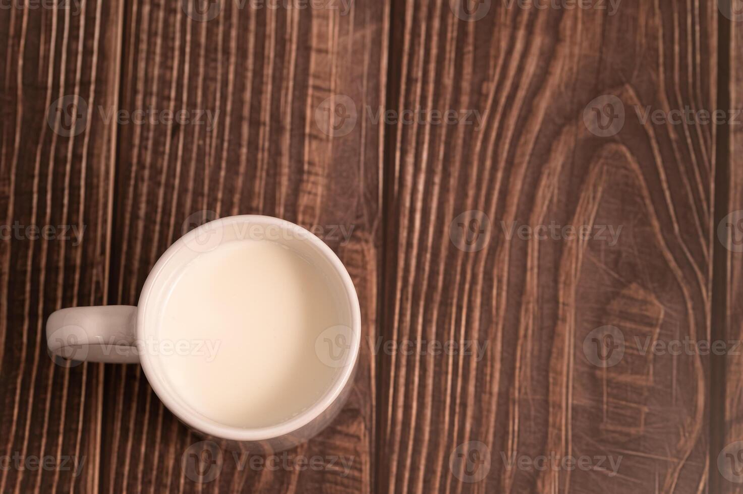 A cup of milk sits on a wooden table photo