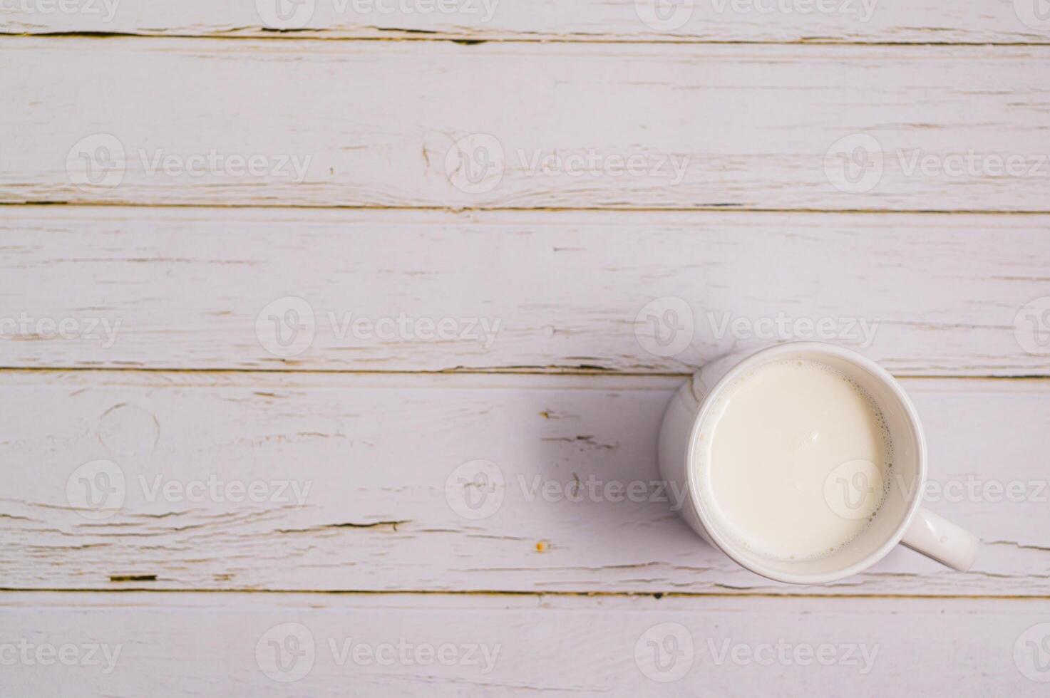 A cup of milk sits on a wooden table photo