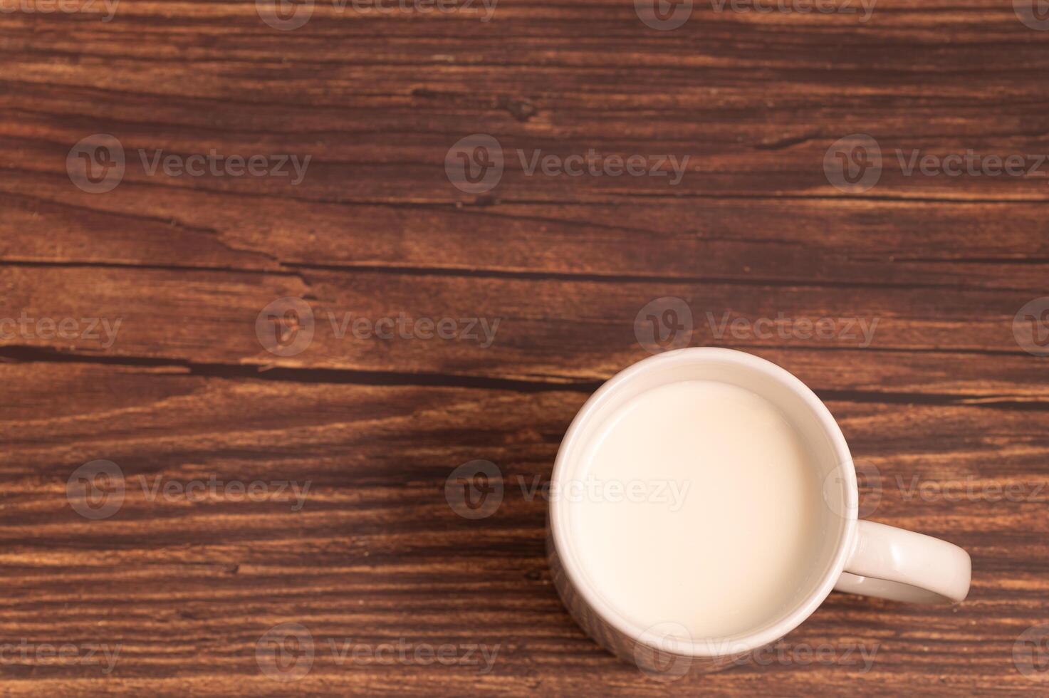 A cup of milk sits on a wooden table photo