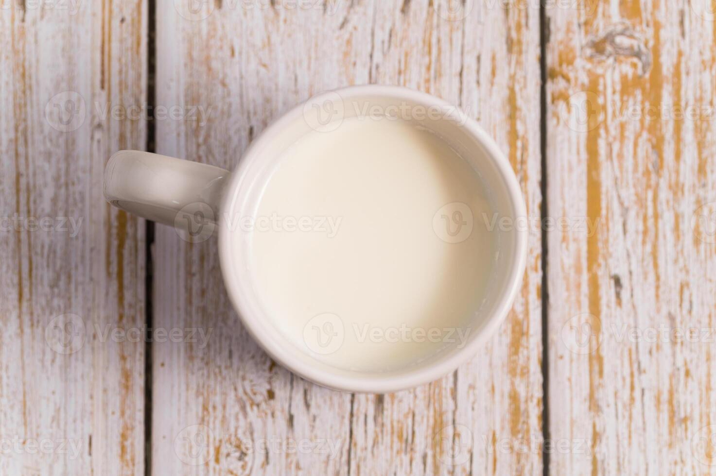 A cup of milk sits on a wooden table photo