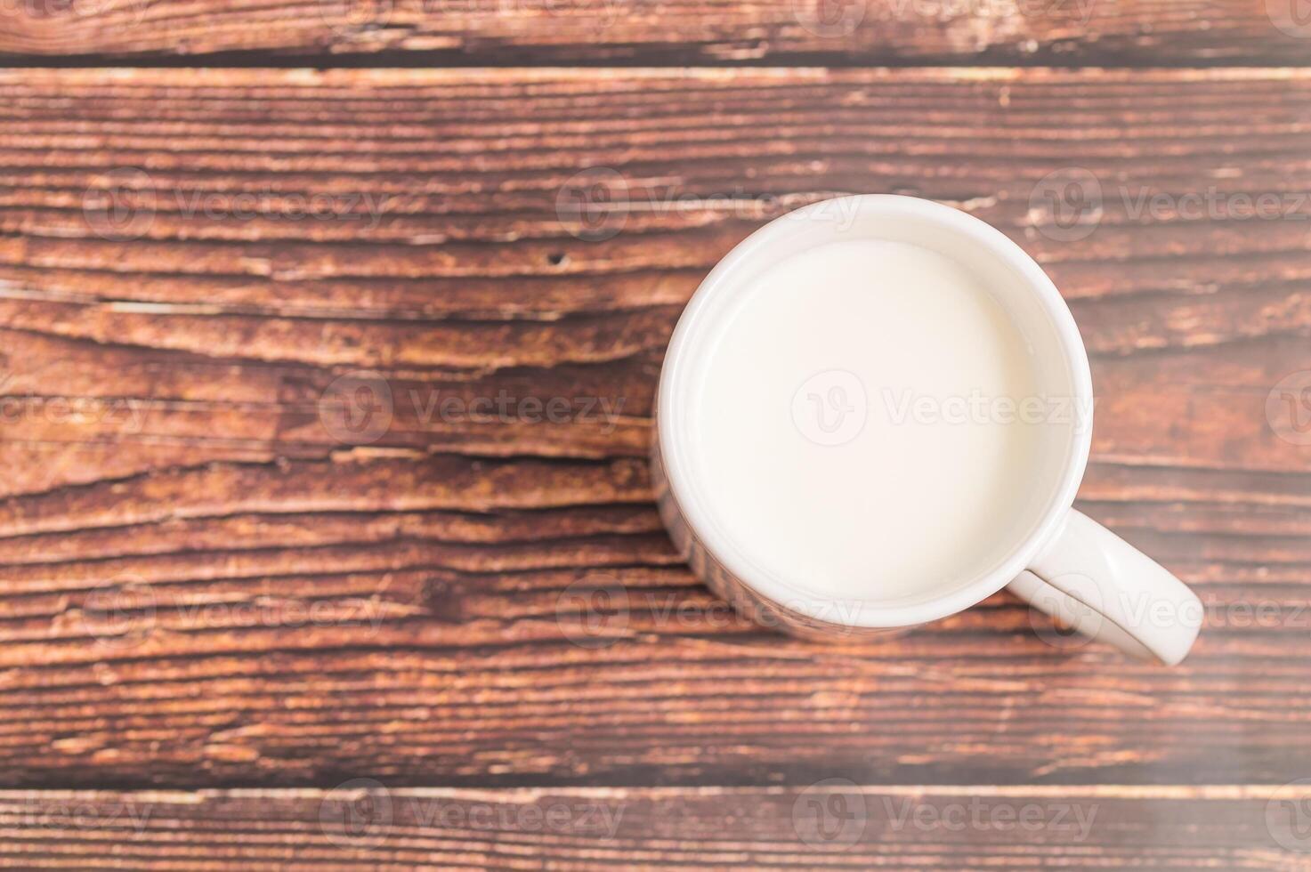 A cup of milk sits on a wooden table photo