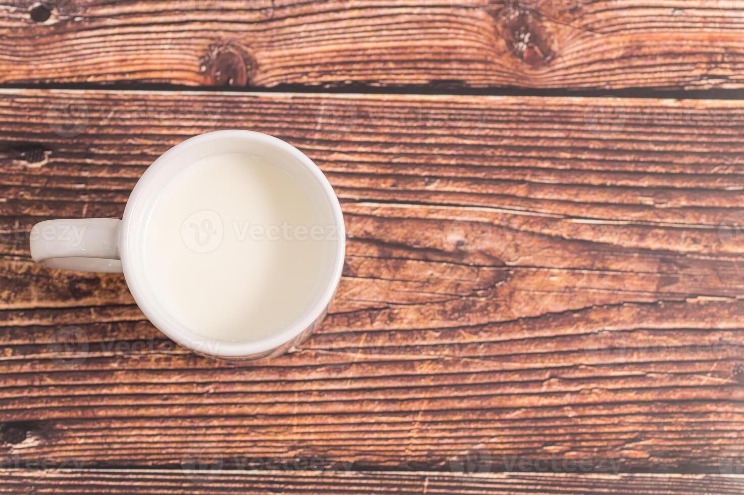 A cup of milk sits on a wooden table photo