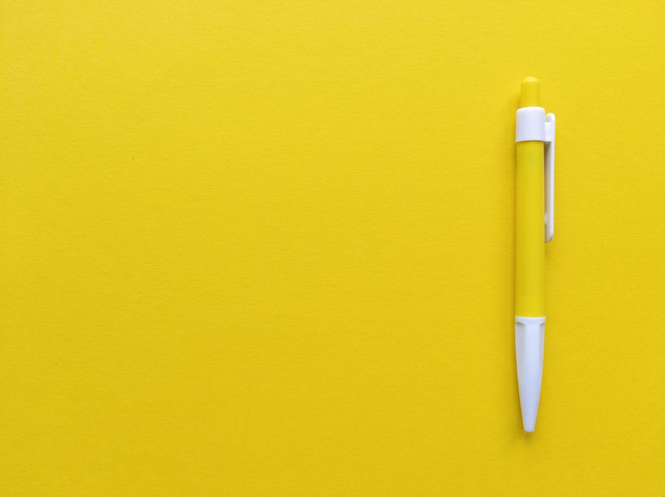 Yellow and white pen on yellow background. Minimalistic flat lay with copy space. Stock photo. photo