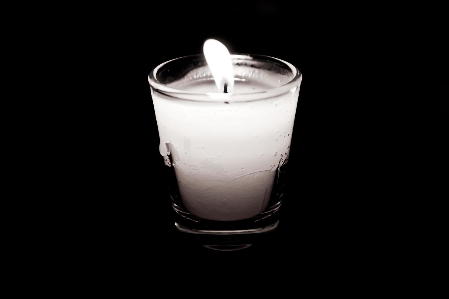 Candle in glass on black background photo