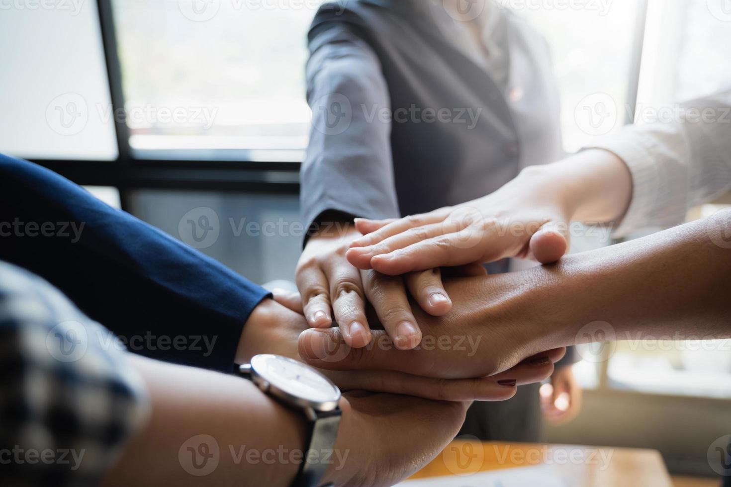 Group of businesspeople putting their hands working together in an office. Group support, teamwork agreement concept. photo