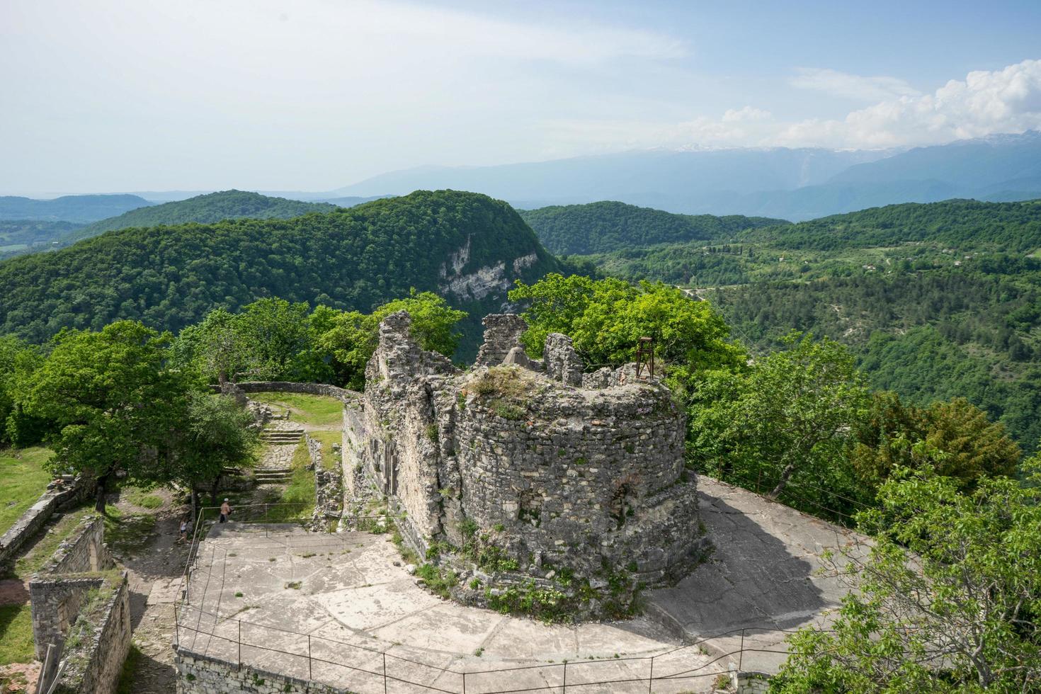 Part of Anacopia Fortress overlooking green forest and mountains with a clear blue sky in New Athos, Abkhazia photo