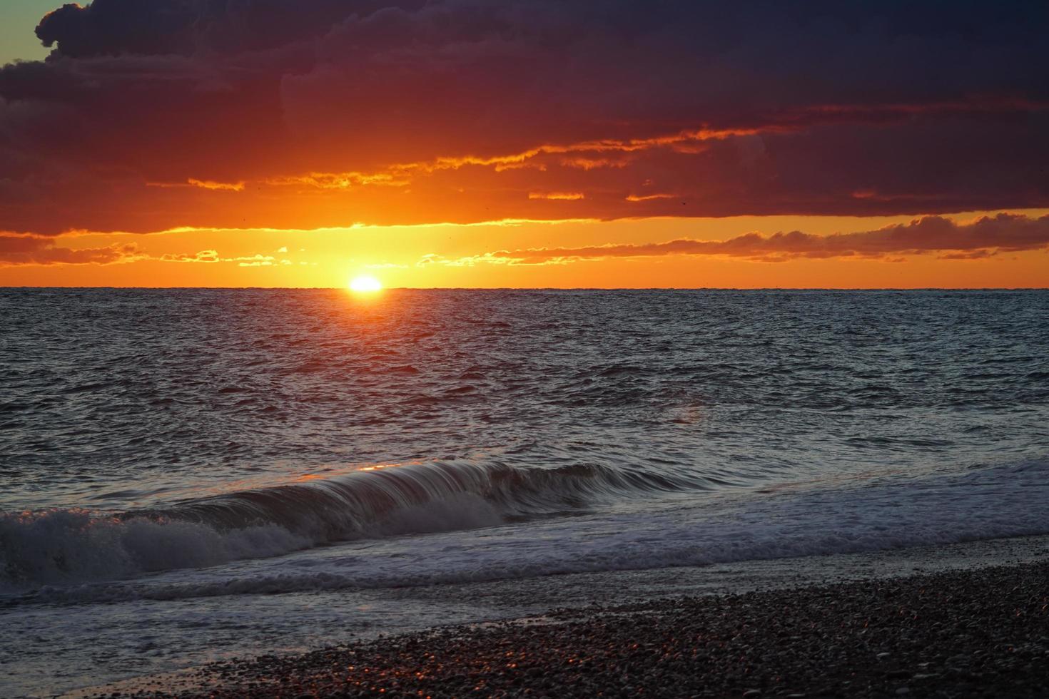 Colorido atardecer nublado naranja sobre un cuerpo de agua foto