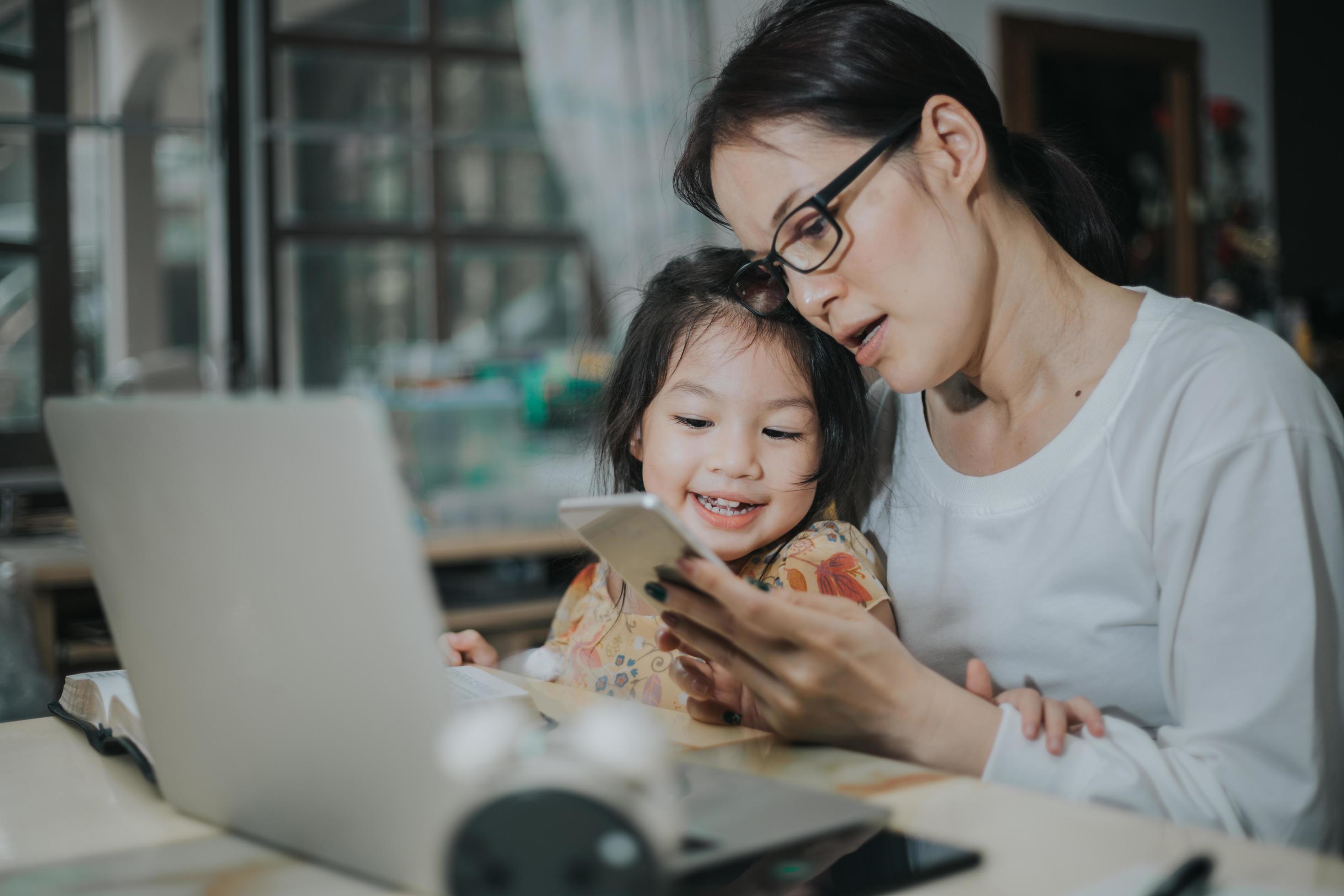 Asian woman teaching her daughter with laptop and smartphone, studying  online concept. 2289302 Stock Photo at Vecteezy