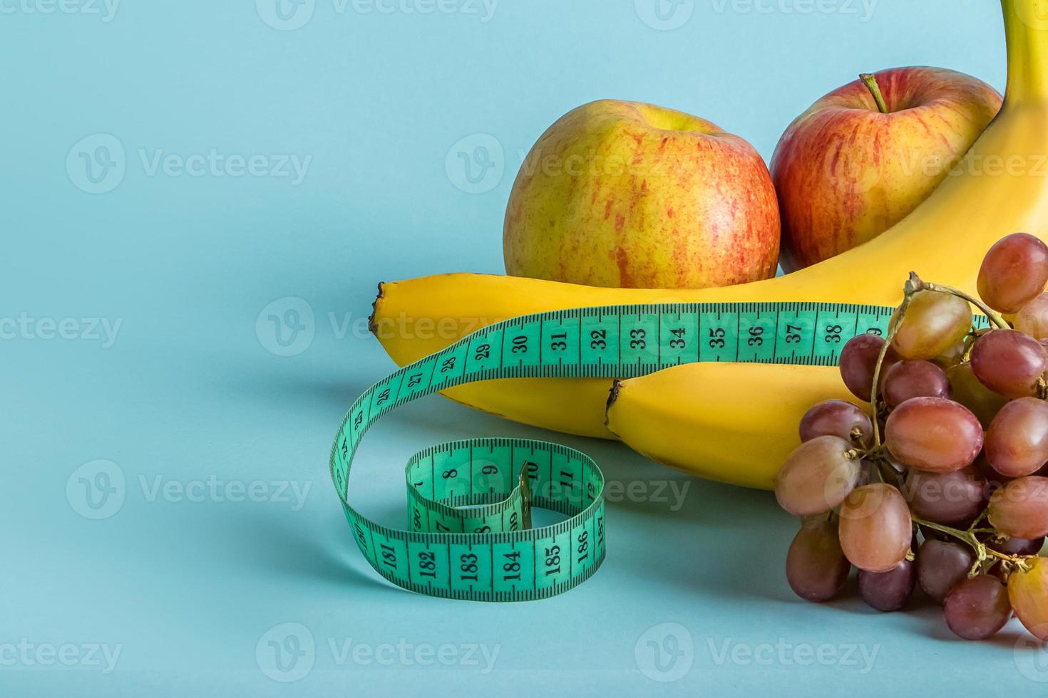 frutas maduras y cinta métrica sobre un fondo azul. el concepto de dieta y nutrición adecuada. foto