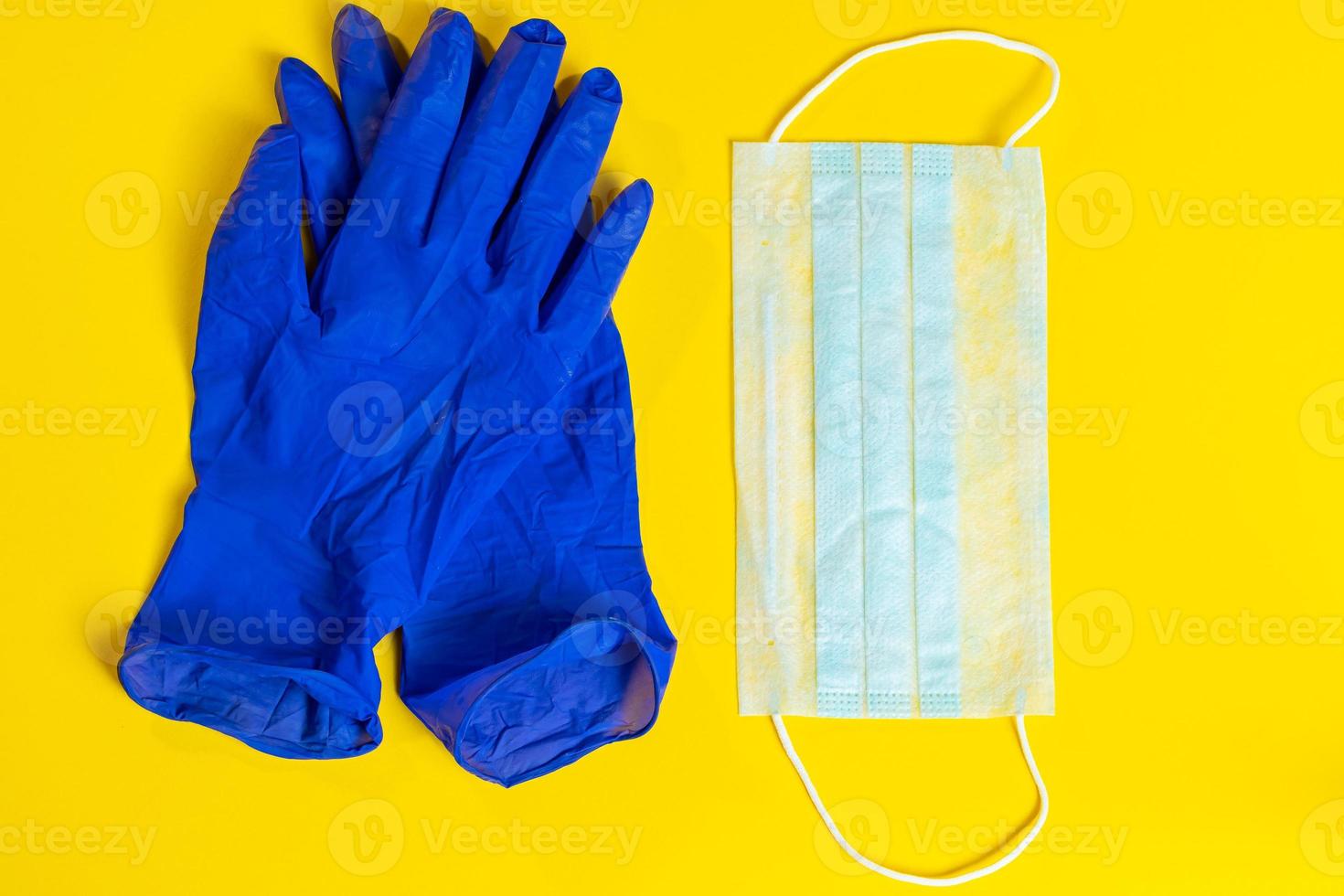 Latex gloves and medical face mask on a yellow background. Preventive protection against coronavirus. photo