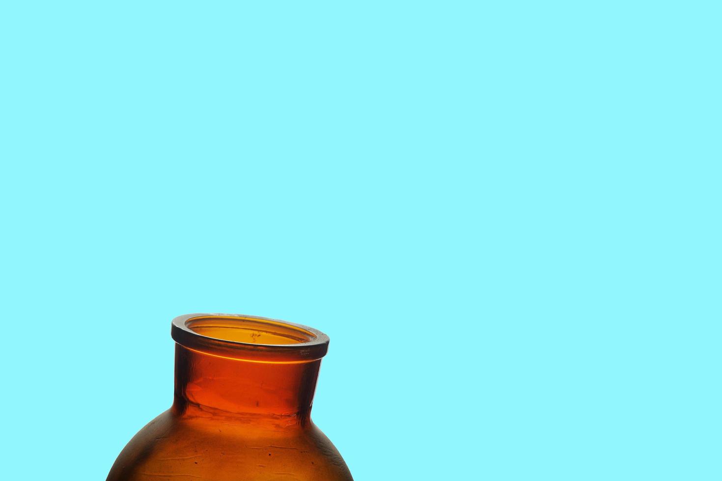 Dusty open jar on bright aqua blue background. Red brown jar on blue. photo