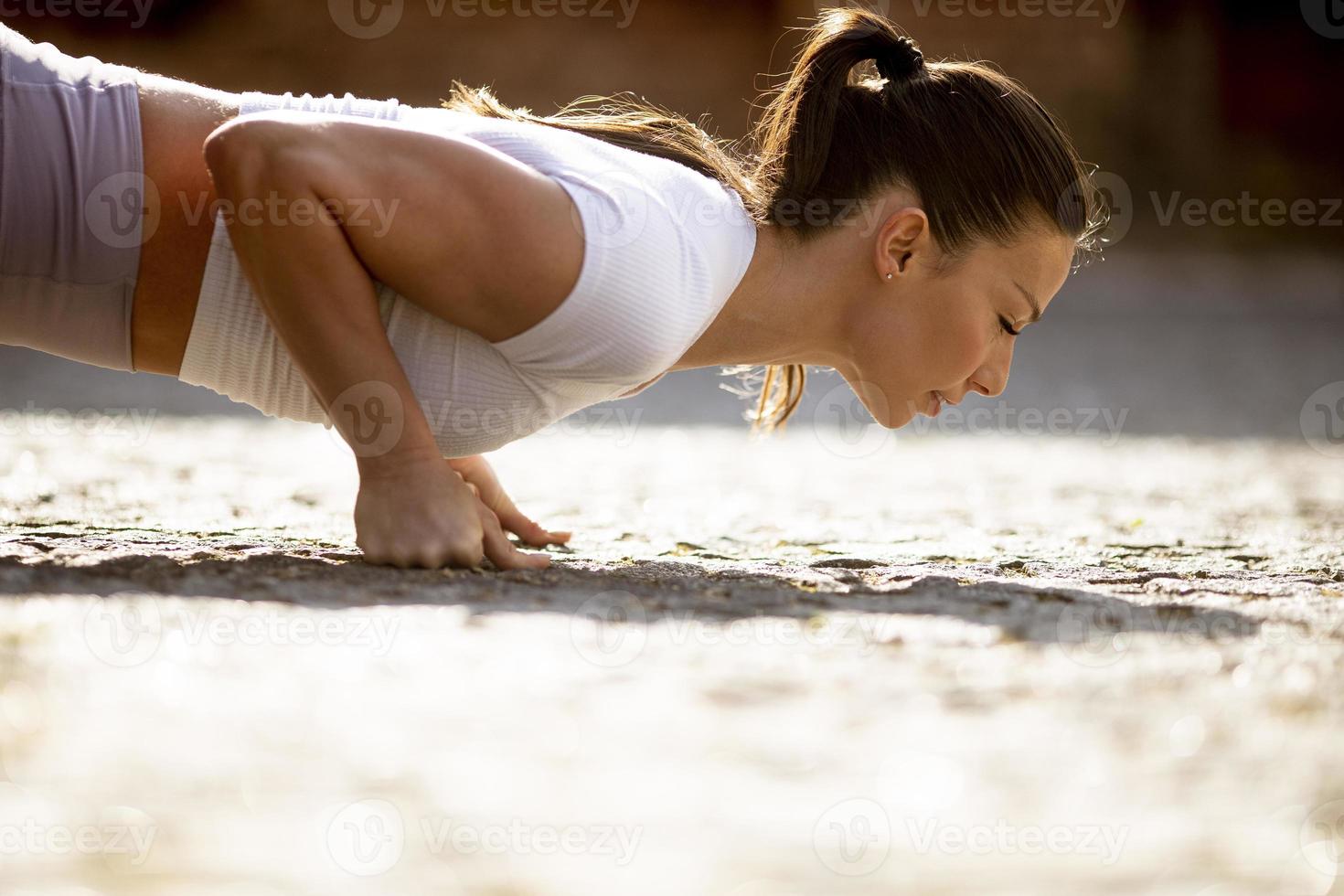 Pretty young woman doing push ups on the street photo