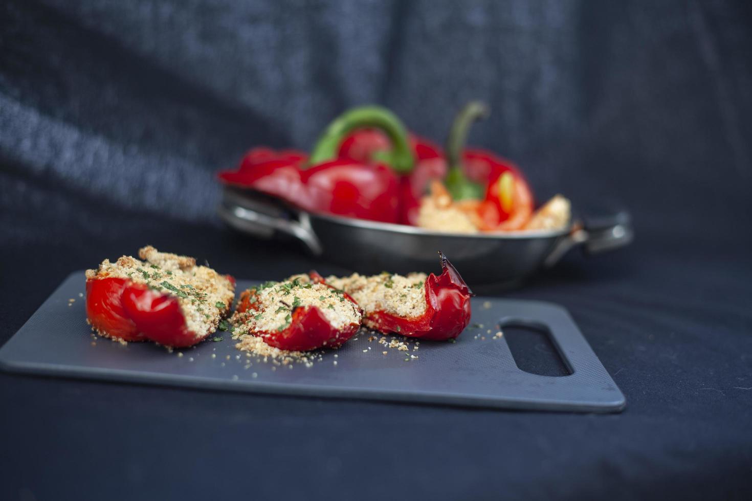 pimientos rojos rellenos en un plato y tabla de cortar foto