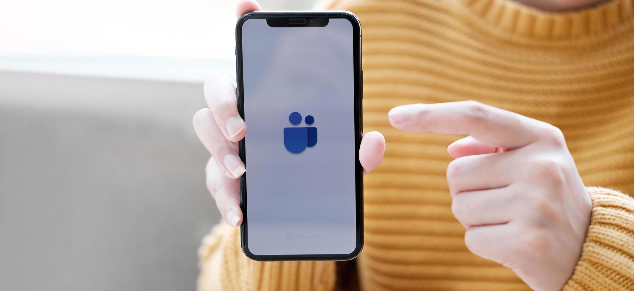 Chaing Mai, Thailand, Apr 11, 2021 - Person pointing to a phone with Microsoft Teams on it photo