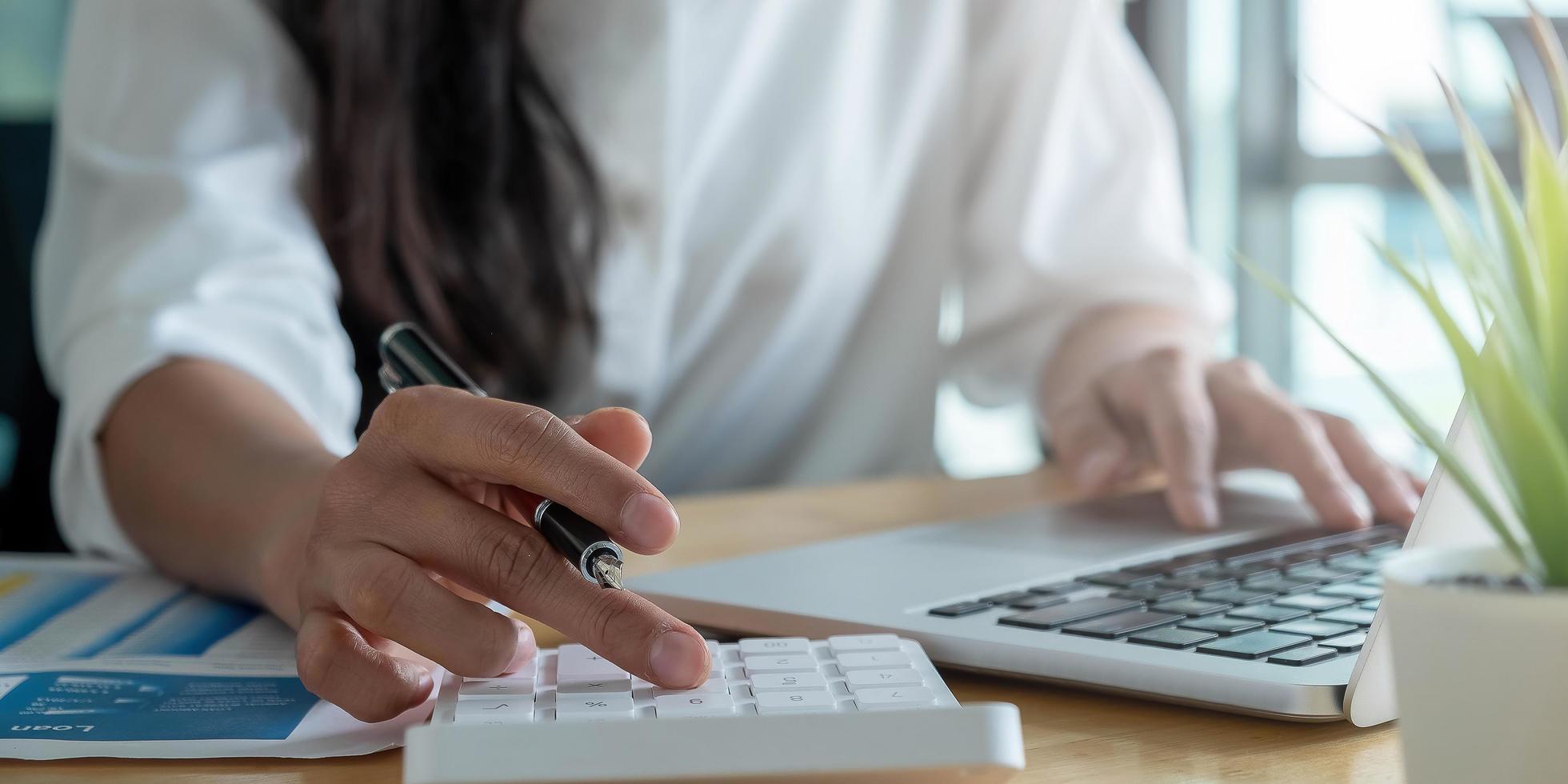 primer plano, de, un, mujer, utilizar, un, calculadora, y, computadora portátil foto