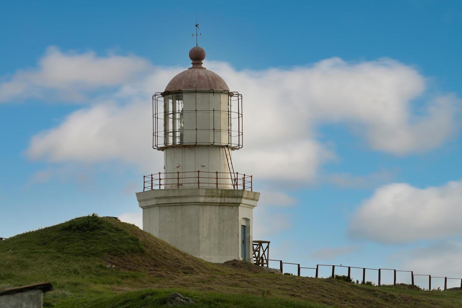 Lighthouse at Cape Pospelova with a cloudy blue sky in Nakhodka, Russia photo