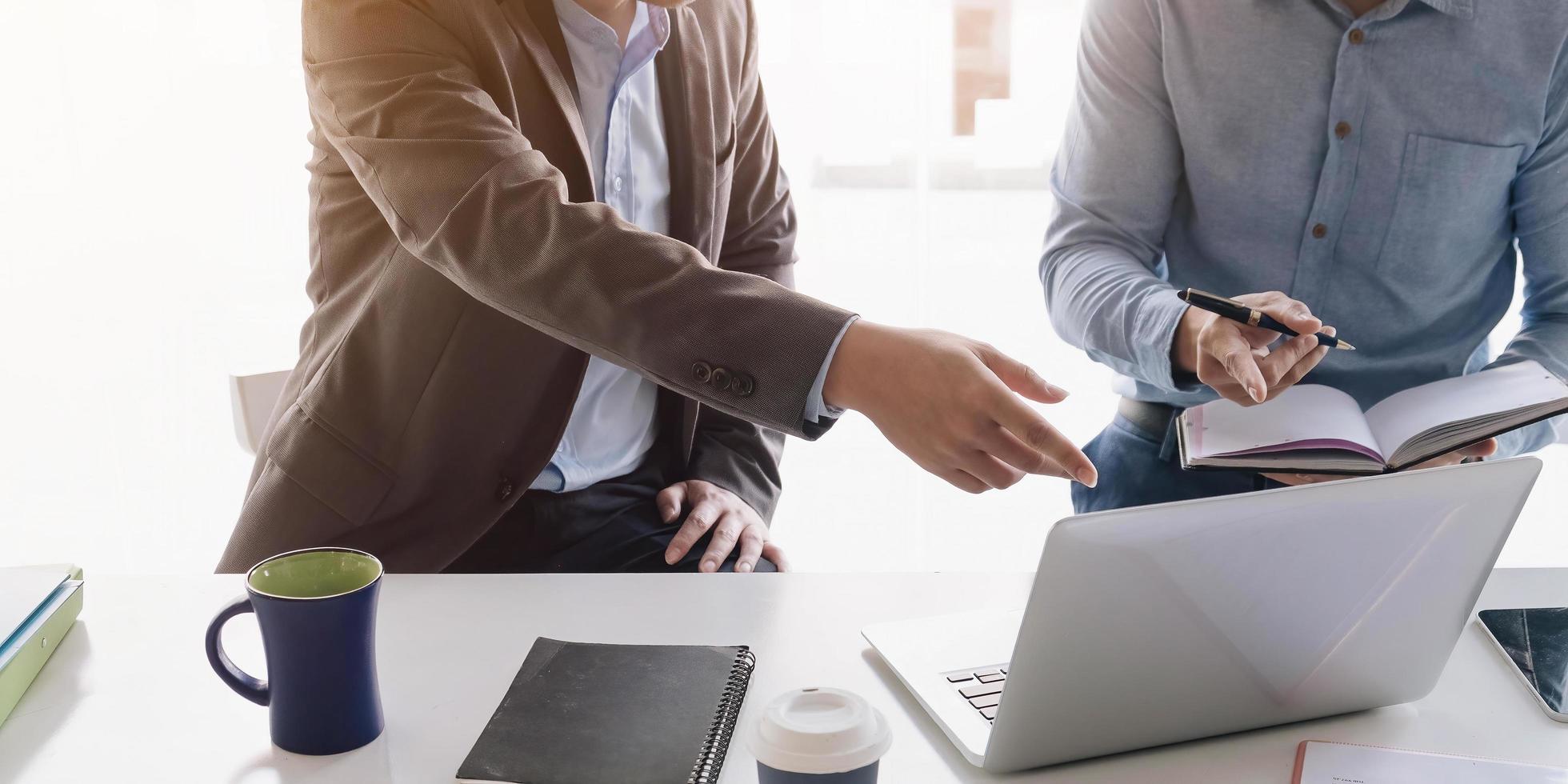 profesionales de negocios apuntando a una computadora portátil foto