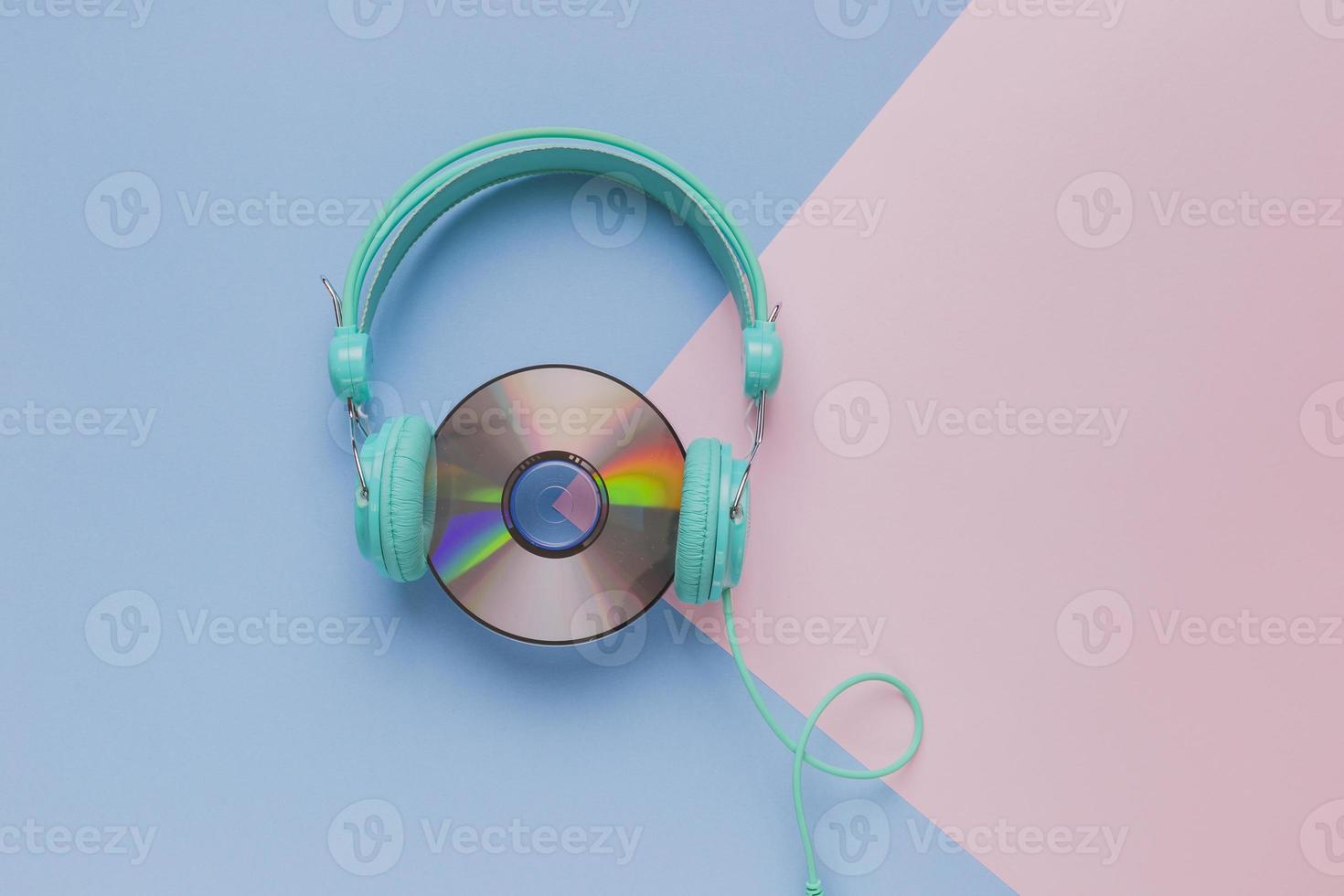 CD with headphones on pastel blue and pink background photo