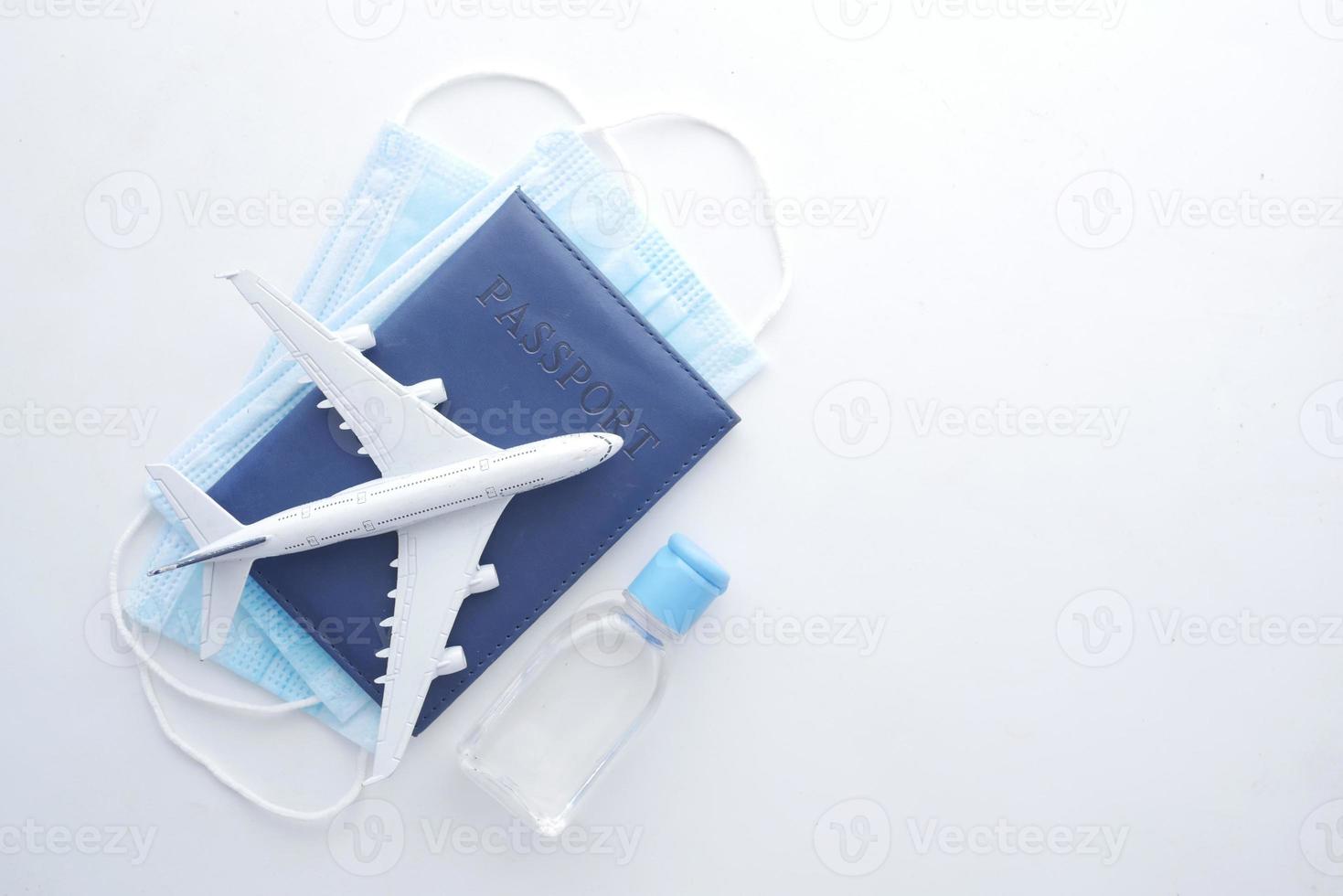 Avión con máscaras protectoras y desinfectante de manos sobre un fondo blanco. foto