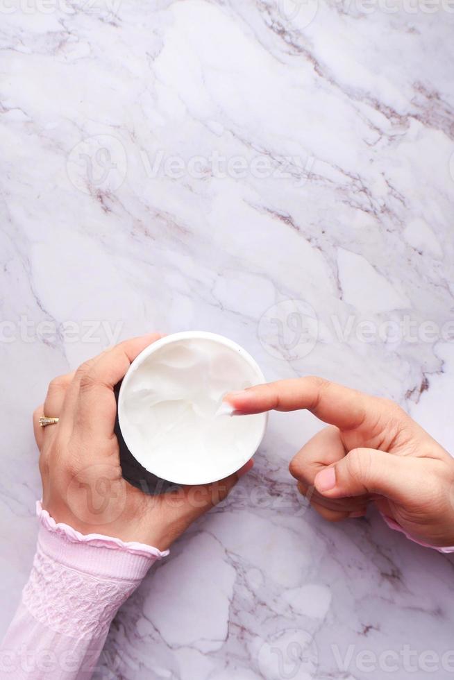 Woman applying beauty cream onto skin photo