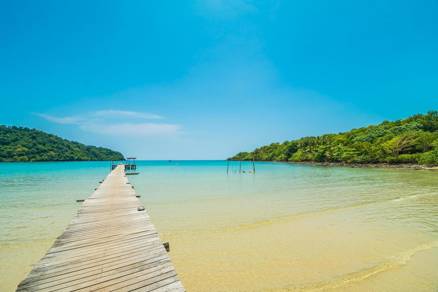 Wooden pier or bridge with tropical beach and sea in paradise island photo