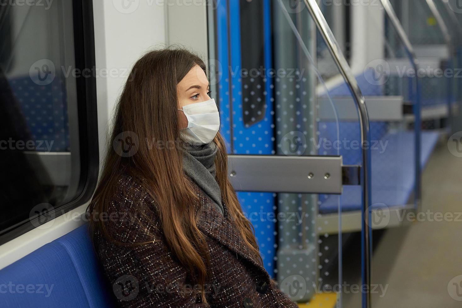 una mujer con una mascarilla médica mantiene la distancia social en un moderno vagón de metro foto