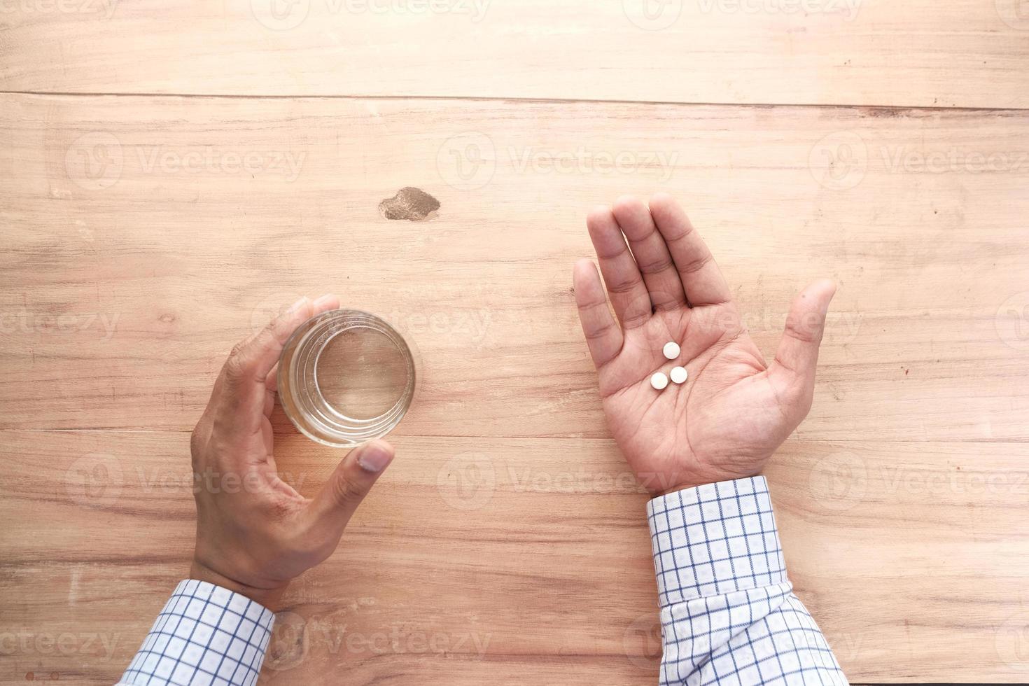 Top view of a person holding pills and water photo