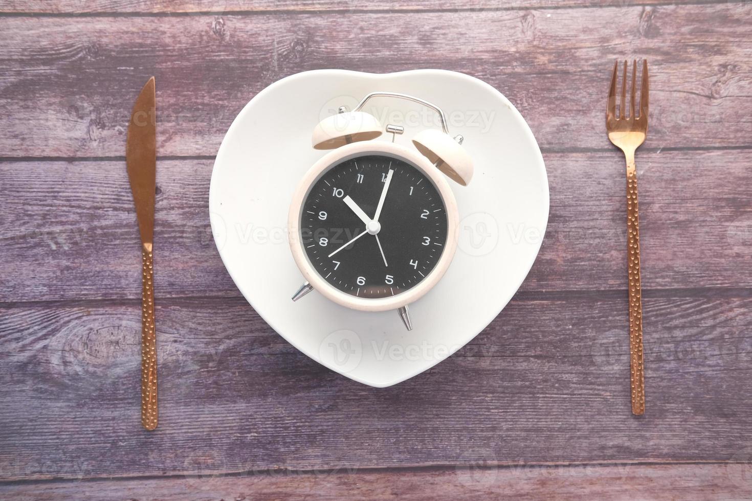 Alarm clock on a heart-shaped plate top view photo