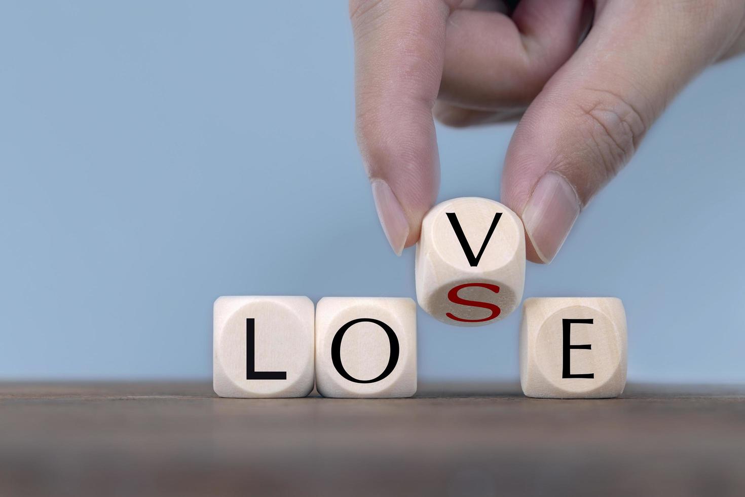 Hand changing word from love to lose on wooden cubes photo