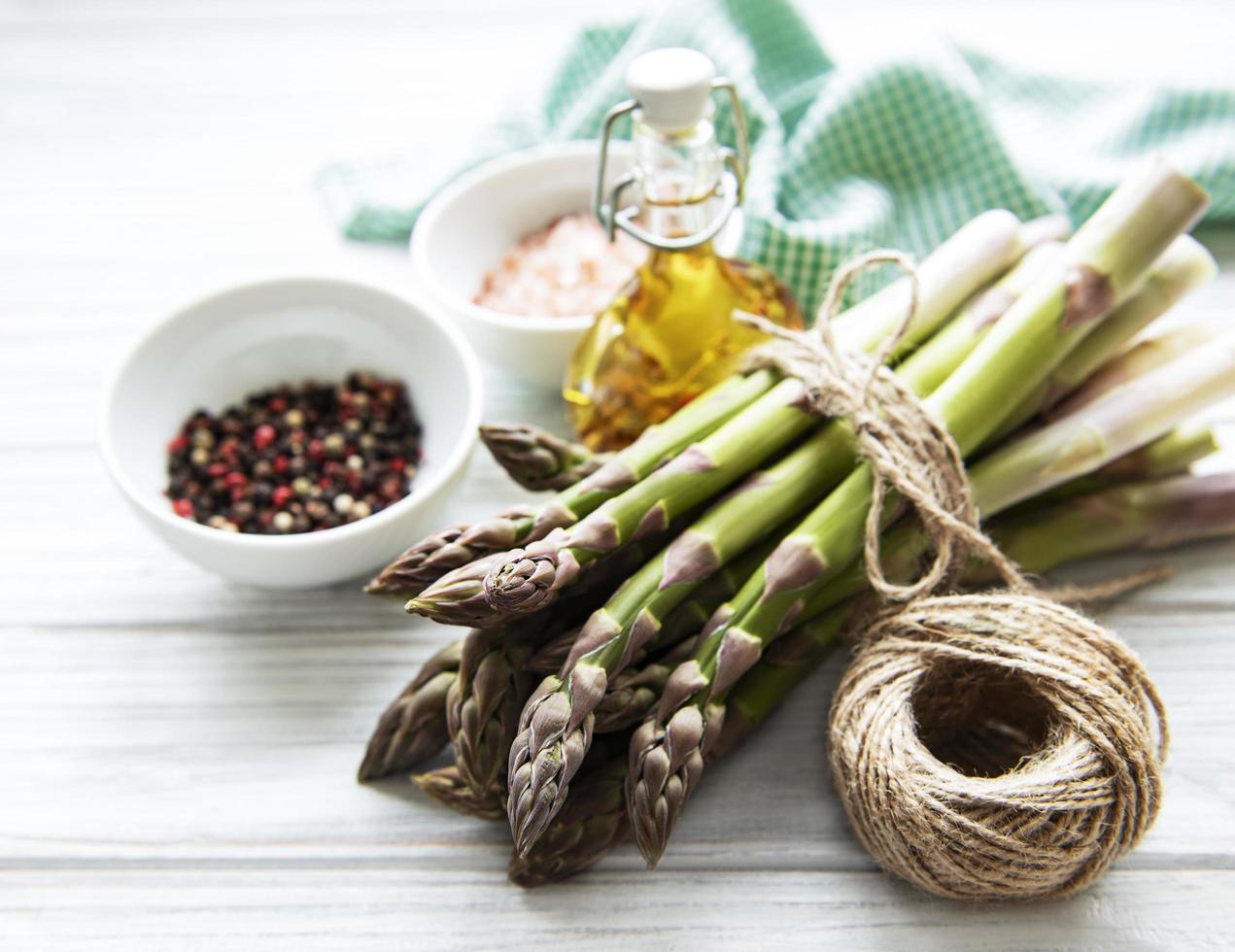 Bunch of raw asparagus stems with different spices photo