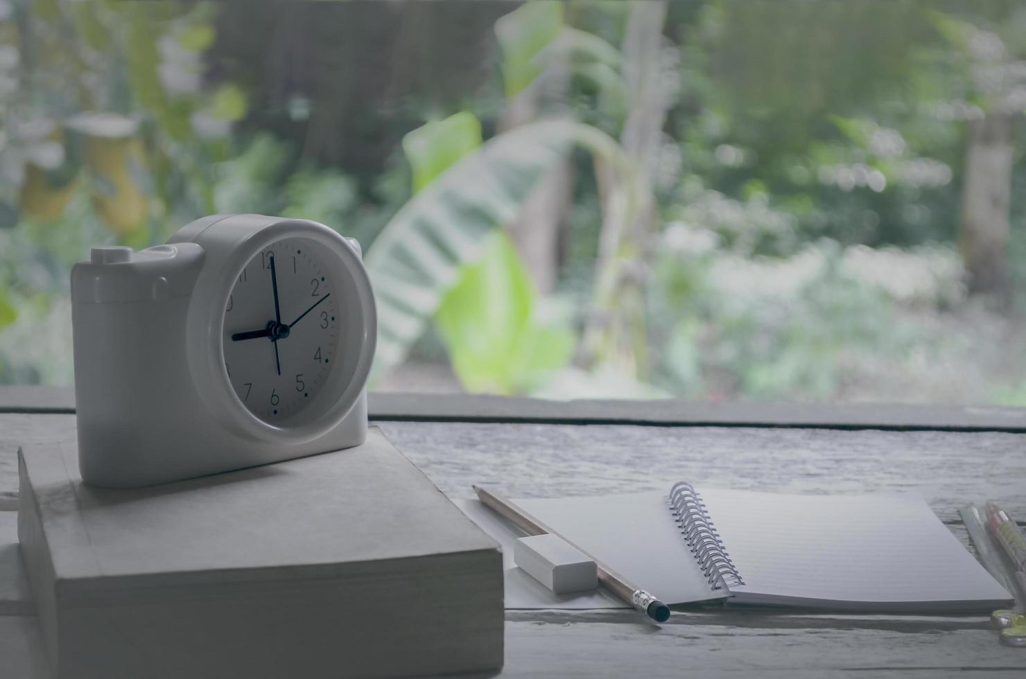 Aula vintage en el fondo de la naturaleza con cuaderno, lápices y reloj despertador foto