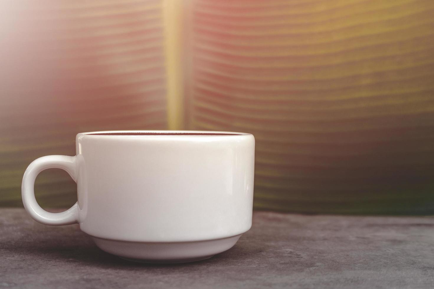 White coffee mug over banana leaf background photo