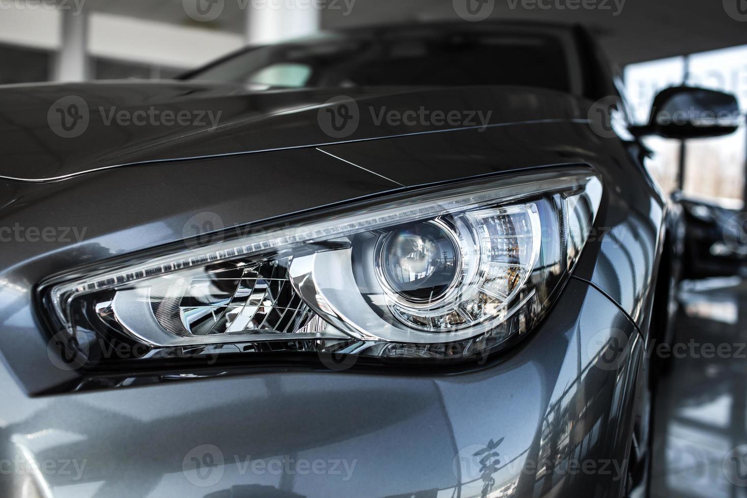 Modern luxury car close-up. Concept of expensive, sports auto. Headlight lamp of new cars, copy space. A modern and elegant car illuminated photo