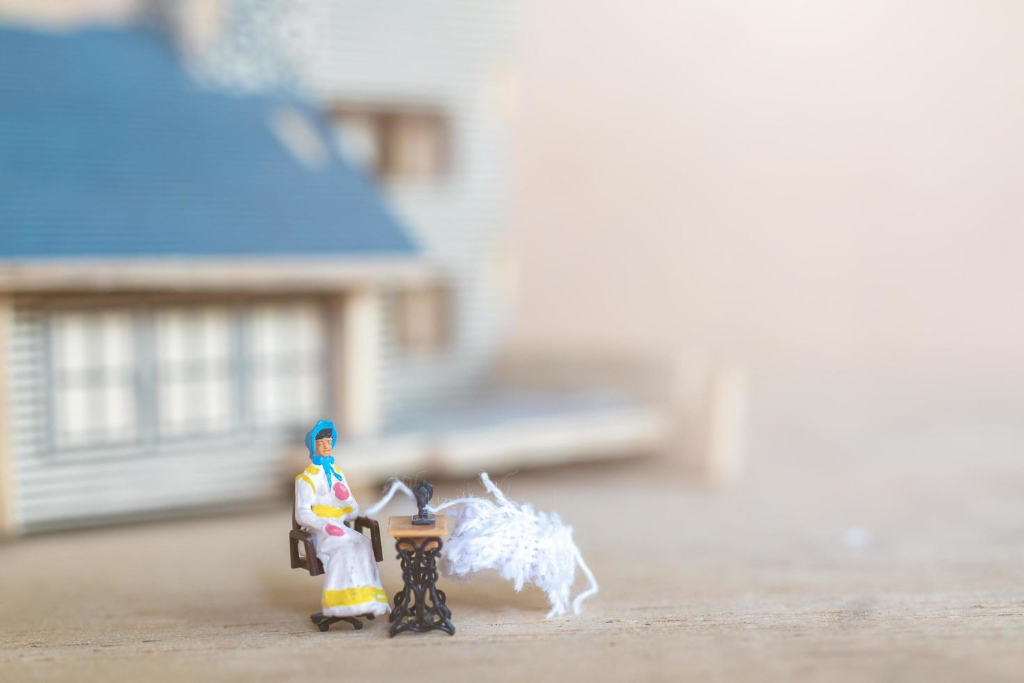 gente en miniatura, mujer cosiendo en una máquina de coser en su casa. Mujer costurera trabajando en una máquina de coser foto